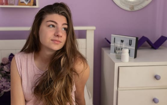 A young woman in her bedroom looking out the window, thinking .Close up horizontal picture.