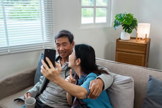 A man and woman are sitting on a couch, both looking at a cell phone. They seem to be enjoying their time together