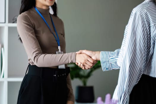 Two businesswomen shake hand after meeting and agreement on partnership and strategy about financial.