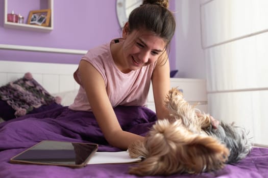 Young girl playing with her dog, on a break from her online classes.