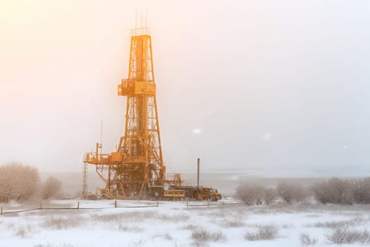 Oil rig in a winter field with a misty background