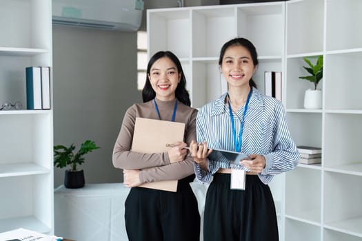 two colleague young professional women smiling confidently in office setting.