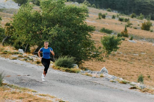 A determined female athlete runs through a forest trail at sunrise, surrounded by breathtaking natural beauty and vibrant greenery.