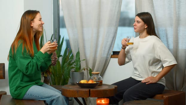 Young women drink tea and have fun chatting in cafe. Media. Young students are having fun talking in cozy college cafe. Women drink tea and laugh in cafe.