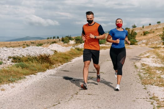 Couple running in nature at morning wearing protective face masks.