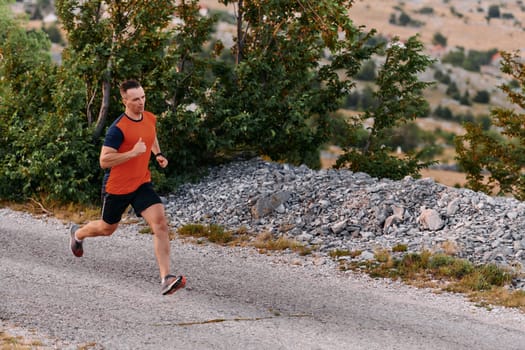 A muscular male athlete runs along a rugged mountain path at sunrise, surrounded by breathtaking rocky landscapes and natural beauty.