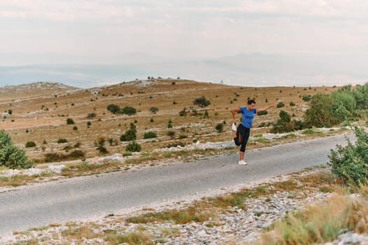 A determined female athlete stretches her muscles after a strenuous run through rugged mountain terrain, surrounded by breathtaking rocky landscapes.