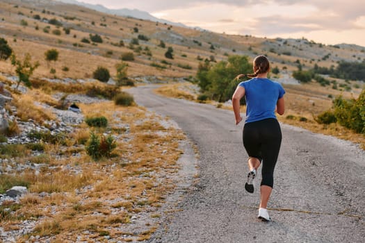 A determined female athlete runs through a forest trail at sunrise, surrounded by breathtaking natural beauty and vibrant greenery.