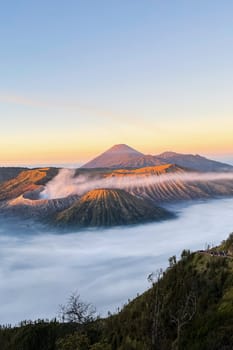 A breathtaking scene of a mountain surrounded by fog during sunset, creating a mystical and serene atmosphere in the natural landscape