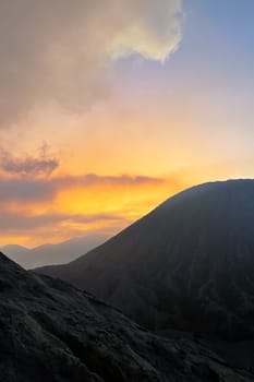 A picturesque scene of a sunset setting behind a majestic mountain in the foreground, creating a stunning natural landscape with vibrant colors in the sky and atmosphere