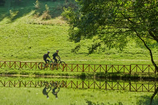 A blissful couple, adorned in professional cycling gear, enjoys a romantic bicycle ride through a park, surrounded by modern natural attractions, radiating love and happiness.