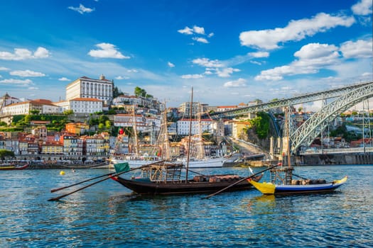 View of Porto city and Douro river with traditional boats with port wine barrels and sailing ship from famous tourist viewpoint Marginal de Gaia riverfront. Porto, Vila Nova de Gaia, Portugal