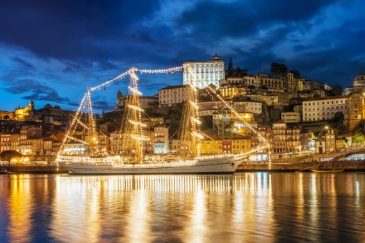 View of Porto city and Douro river with sailing ship from famous tourist viewpoint Marginal de Gaia riverfront in the evening. Porto, Vila Nova de Gaia, Portugal