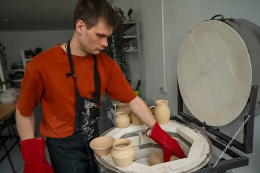 Caucasian man loading ceramic products into a special kiln