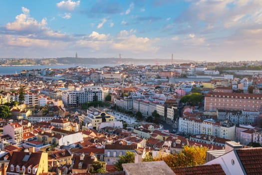 View of Lisbon famous view from Miradouro da Senhora do Monte tourist viewpoint of Alfama and Mauraria old city districts, 25th of April Bridge on sunset. Lisbon, Portugal