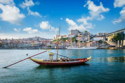 View of Porto city and Douro river with traditional boats with port wine barrels and sailing ship from famous tourist viewpoint Marginal de Gaia riverfront. Porto, Vila Nova de Gaia, Portugal