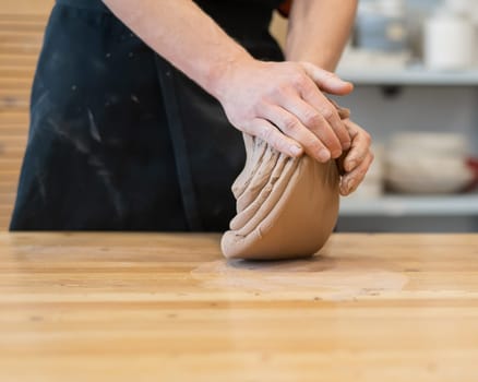 A potter kneads clay before using it in the workshop. Close-up of a man's hands