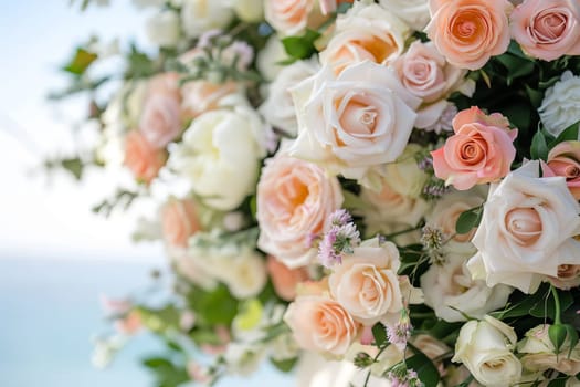 Floral backdrop for a seaside wedding ceremony - an arch decorated with delicate pastel roses and peonies in shades of peach, pink, white and lavender, against a backdrop of sky and ocean waves.