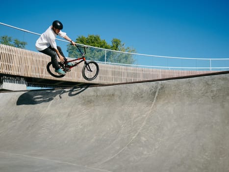 BMX rider performing aerial trick Toboggan on concrete quarter pipe in skatepark. Skilled BMX freestyler jumping over quarter pipe ramp skatepark. Young BMX bicycle rider having fun and posing. Copy space