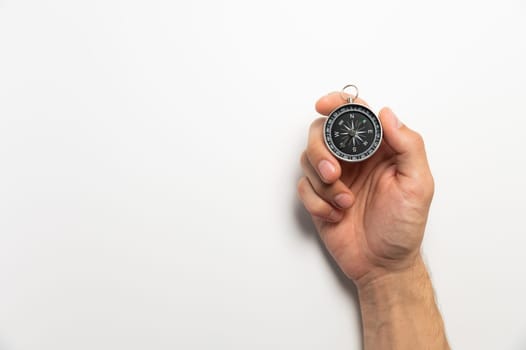 Male hand holding magnetic compass on white background with copy space.