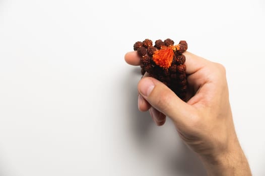 Selective focus, man's hands holding wooden rosary beads on white background.