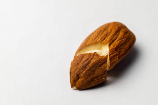 Close-up of one cracked almond seed on a white background.