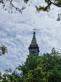 BUDAPEST, HUNGARY - 2023-05-06: Picture the majestic white dome of an church piercing the sky, framed by the vibrant green leaves of tall trees. The juxtaposition of earthly foliage and heavenly architecture creates a scene of profound spiritual harmony, inviting contemplation and awe.