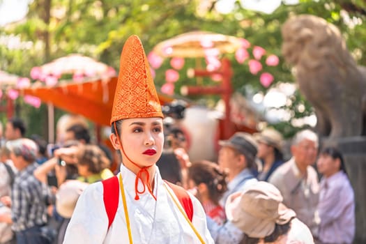 tokyo, asakusa - may 17 2024: A bust portrait of a Japanese lady in white heron dancer attire wearing a traditional embroidered eboshi hat captivates audience at Sensoji Temple during Sanja Matsuri.