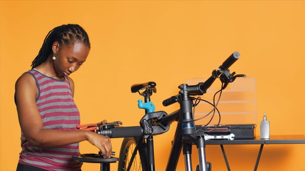 African american mechanic preparing work tools before starting repairing broken client bicycle, studio background. Professional arranging mechanical equipment, ready to start fixing bike, camera A