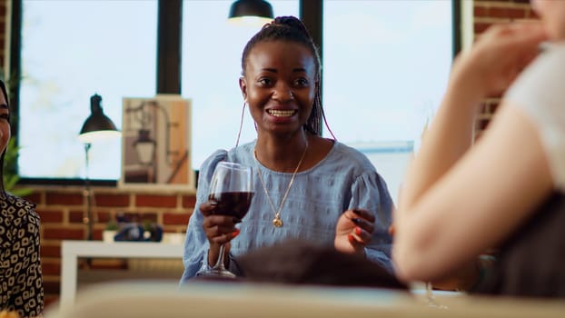 African american woman discussing with diverse apartment party guests about her boyfriend, making them laugh with hilarious tales. Happy group of people listening to host talking about partner