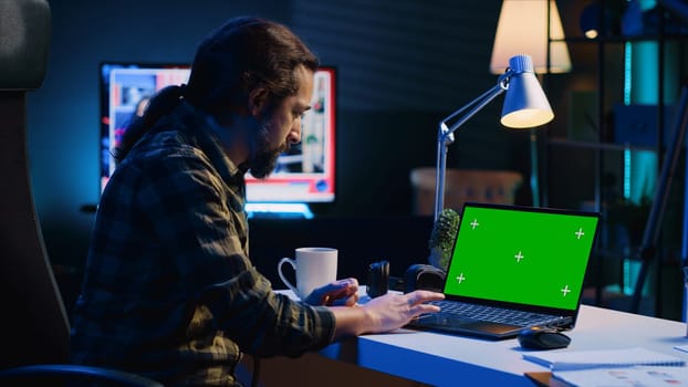 Teleworker in living room office using chroma key laptop to answer emails from business associates. Remote employee typing on isolated screen device keyboard, solving tasks in apartment