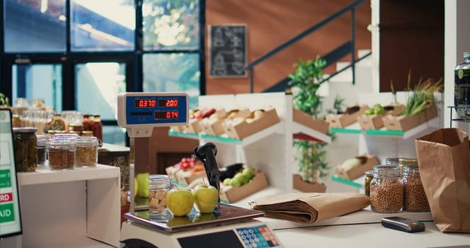 Grocery store scale used to sell bulk items and weight goods at cash register checkout, sustainable lifestyle. Market with freshly harvested produce and homemade pantry essentials. Handheld shot.