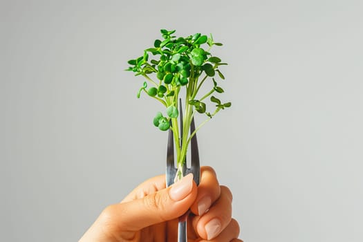 A person holds a fork with a sprout of microgreen on it.