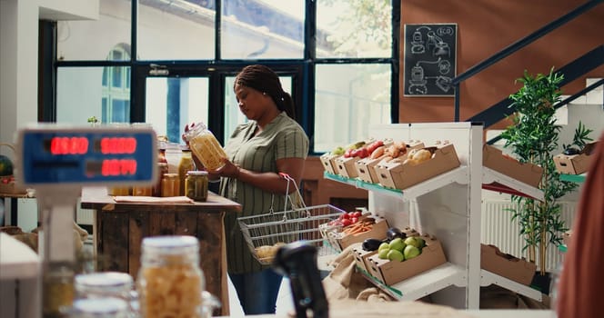 African american client opening jars filled with bulk items to buy chemicals free products and supplies. Woman searching for eco friendly vegan food alternatives, nonpolluting concept. Handheld shot.