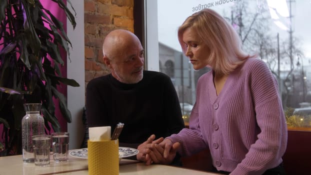 Beautiful elderly couple on date in cafe. Stock footage. Beautiful elderly couple is chatting on date. Stylish elderly couple chatting in cafe.