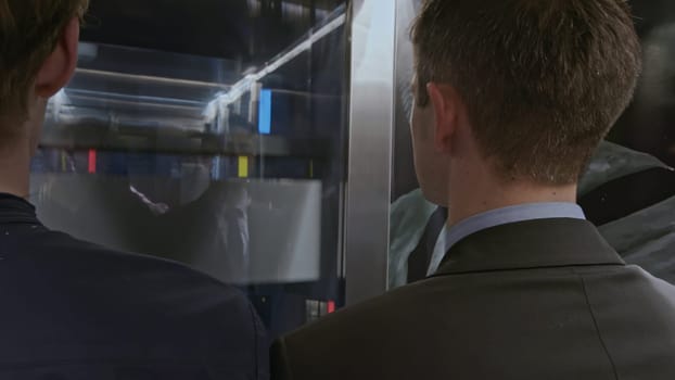 Team of start up businesspeople entering modern elevator and discussing corporate meeting. Stock clip. Businessmen using elevator to get to upper floor of business center