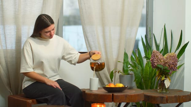 Young woman enthusiastically drinks tea in cafe. Media. Young woman drinks warming tea in cozy cafe by window in winter. Warming tea in cozy cafe on winter day.