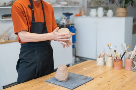 A potter kneads clay before using it in the workshop. Close-up of a man's hands