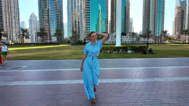 Young adult elegant beautiful woman on big city street background. Action. Lady in blue suit walking in city park