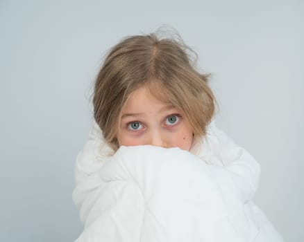 Portrait of a cute little girl wrapped in a white blanket