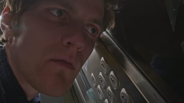 Close up of man listening carefully to the noise of elevator malfunction and pressing the floor button. Stock clip. Men risking to use the faulty elevator
