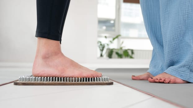 Caucasian woman stands on sadhu boards with therapist support