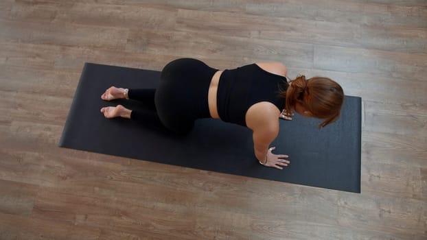 Beautiful sporty girl practicing yoga or pilates at home. Media. Top view of a woman doing balance exercise and stretching her arm and leg