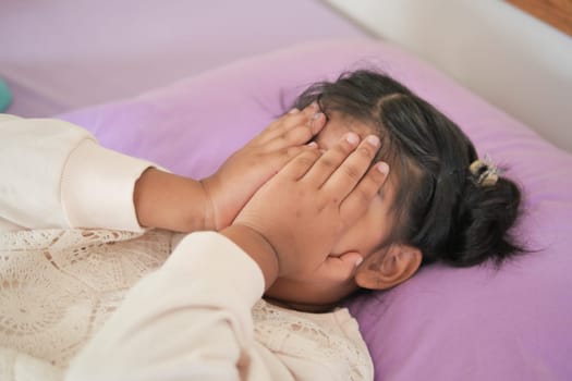 a upset child girl cover her face with hand .