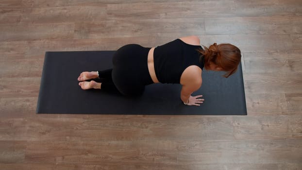 Beautiful Caucasian woman doing fitness on mat at home. Media. Top view of a girl performing exercises