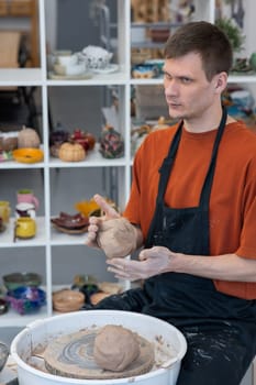 A potter kneads clay before using it on the potter's wheel. Vertical photo