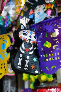 Day of the dead pinata, skeleton cat with papel picado and other Mexican decorations.