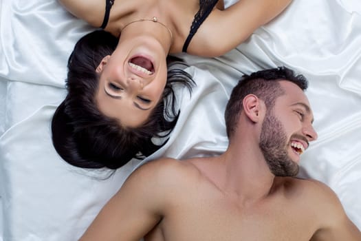 Erotica. Top view of loving couple laughing in bed