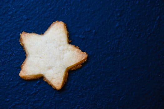 Star shaped Scottish shortbread biscuits, sweets and confectionery, delicious sweet sugar cookies. On dak blue background, looking like a star in the night sky.