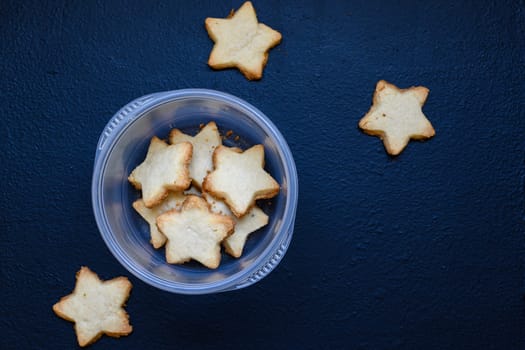 Star shaped Scottish shortbread biscuits, sweets and confectionery, delicious sweet sugar cookies. On dark blue background, looking like stars in the night sky.